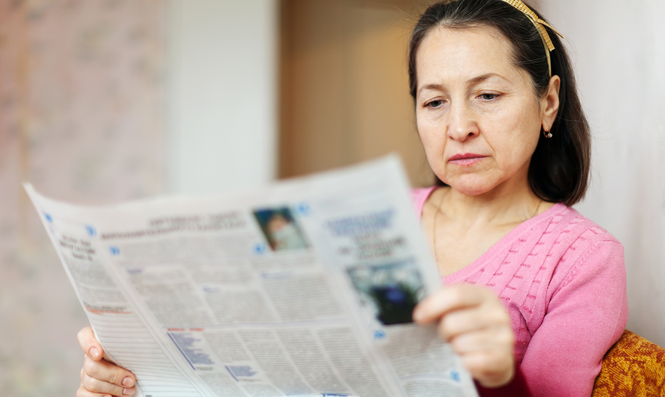 A woman reads a newspaper.